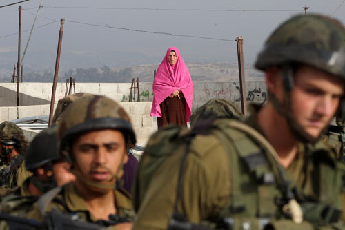Una mujer palestina mira a las tropas israelíes en el pueblo cisjordanao de Beit Ola, cerca de Hebrón, junio 2014. AFP/Getty Images
